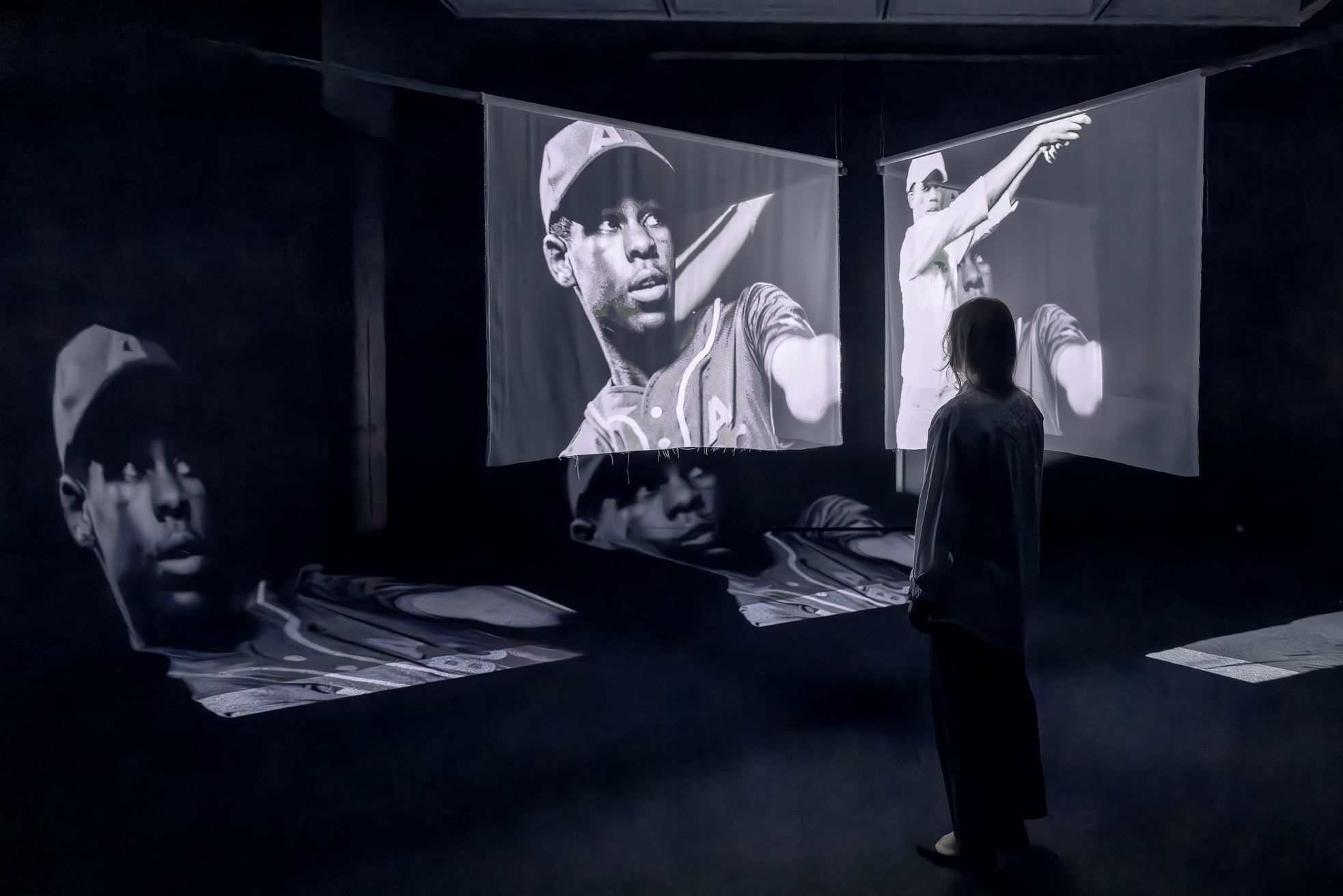Projected image of a historic Black baseball player projected in a dynamic way on hanging screens & the gallery corner