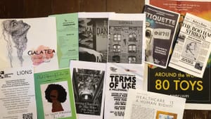12 colorful playbills from different shows laid out together on a wooden table.