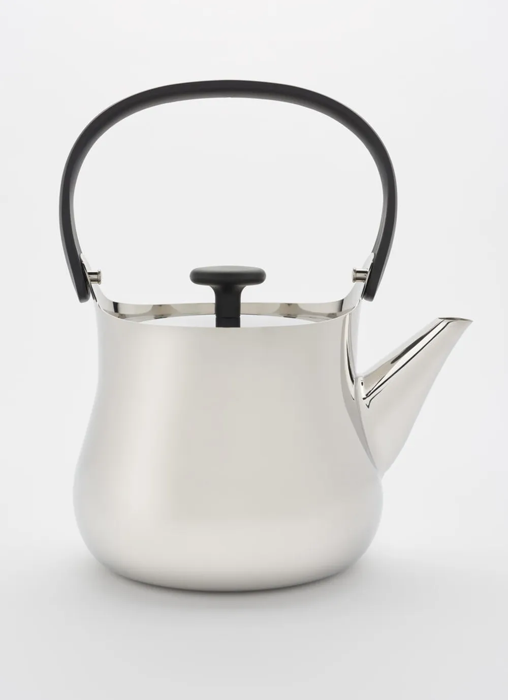 Close-up on a simple teapot in profile, made out of inviting matte silver metal with a gentle curving shape.