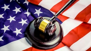 Close-up on a gavel made of polished dark wood with a gold band, on top of an American flag.