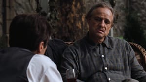 Marlon Brando as the Godfather, sitting in a chair, a wall behind him. A man sits in the foreground, looking towards Brando