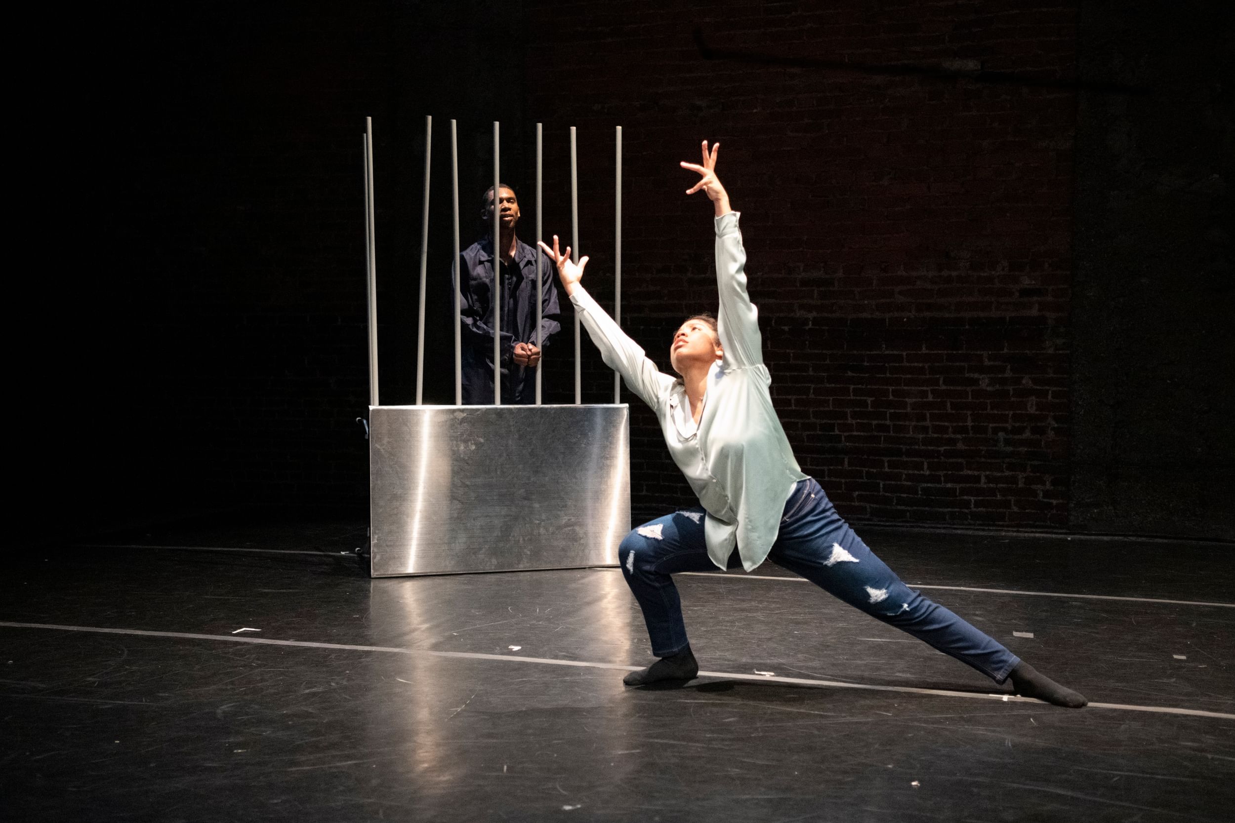 In ripped jeans & baggy white shirt, Cruz squats with one leg outstretched, arms supplicating upward.