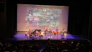 9 musicians, tiny onstage from the back of the house, play in front of a big movie screen with a Parks photo on it.