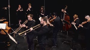 A group of musicians dressed in all black playing various wind instruments.