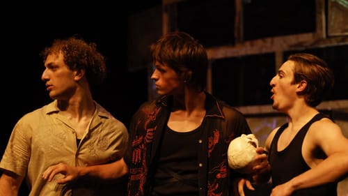 The three men stand together looking to the left, seen from the waist up. Morfitt-Tighe holds a human skull.