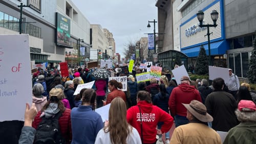 View facing east down Market, with hundreds of marchers under a gray sky facing away from the camera.