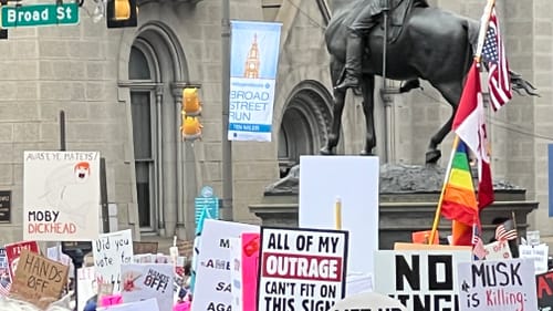 A view of dozens of signs held above protestors’ heads, including “Musk is killing democracy” and a “Moby dickhead” whale