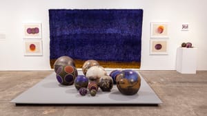 An art gallery view of 11 decorative balls in different colors and textures, from baseball size up to large bowling balls