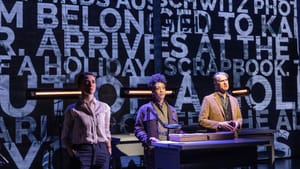 3 actors with grave expressions stand among archivist desks with giant white newsprint words projected on the wall behind.