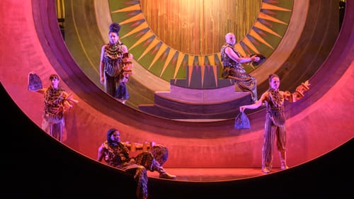 In a set with successive patterned circular frames, the ensemble poses grandly, wearing complex metallic ruched outfits