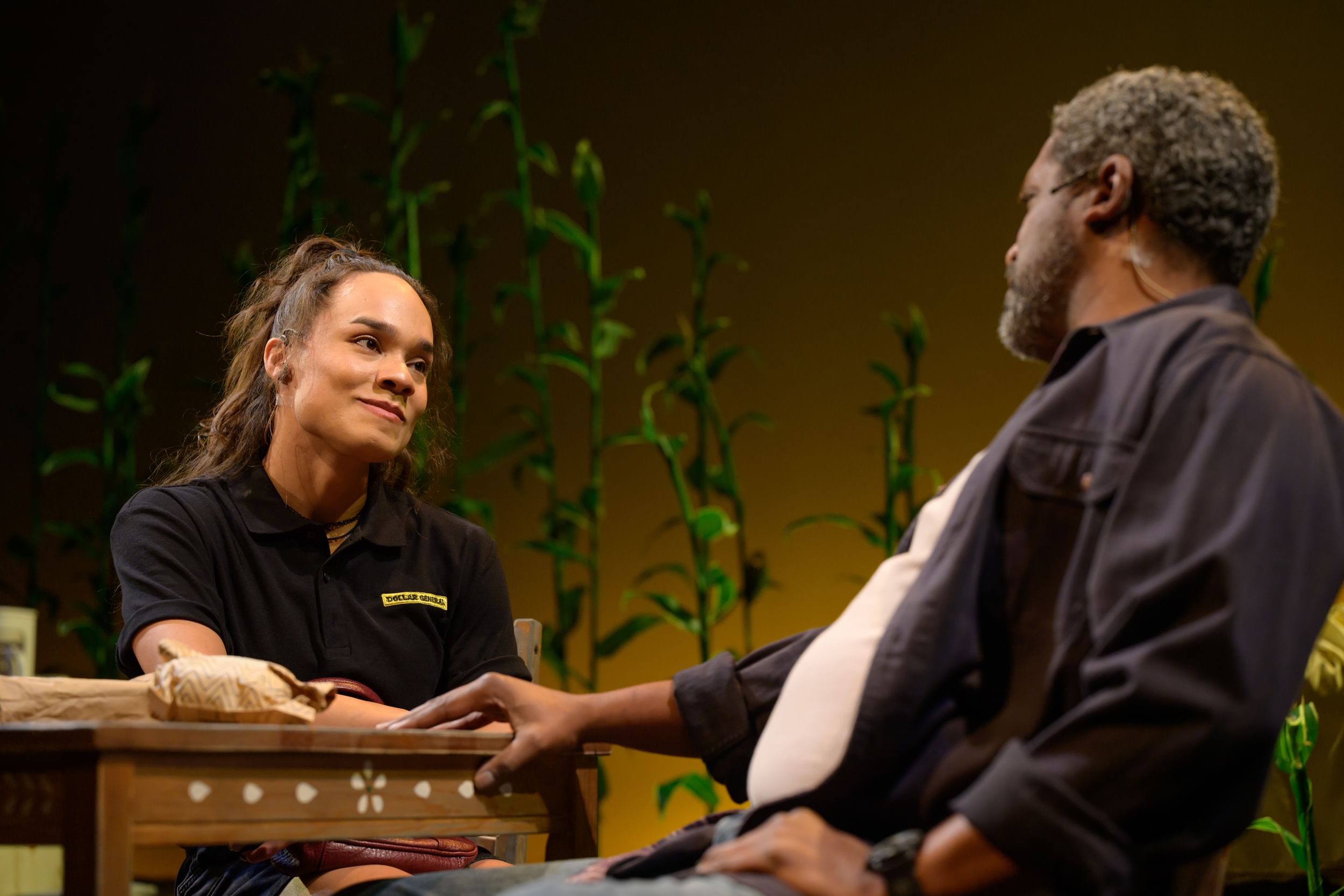 Brisa, a Latina woman, seen seated across the table from Smiling, a Black man, smiles lovingly at him.