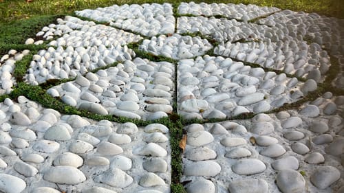 An arrangement of white stones and planters on a grassy area outside in daylight