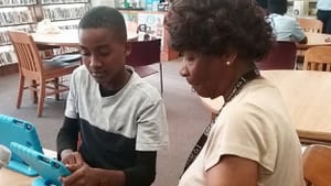 In West Oak Lane, a young PhillyCAM participant helps an older one learn to make a video. (Photo via People's Media Collection.)