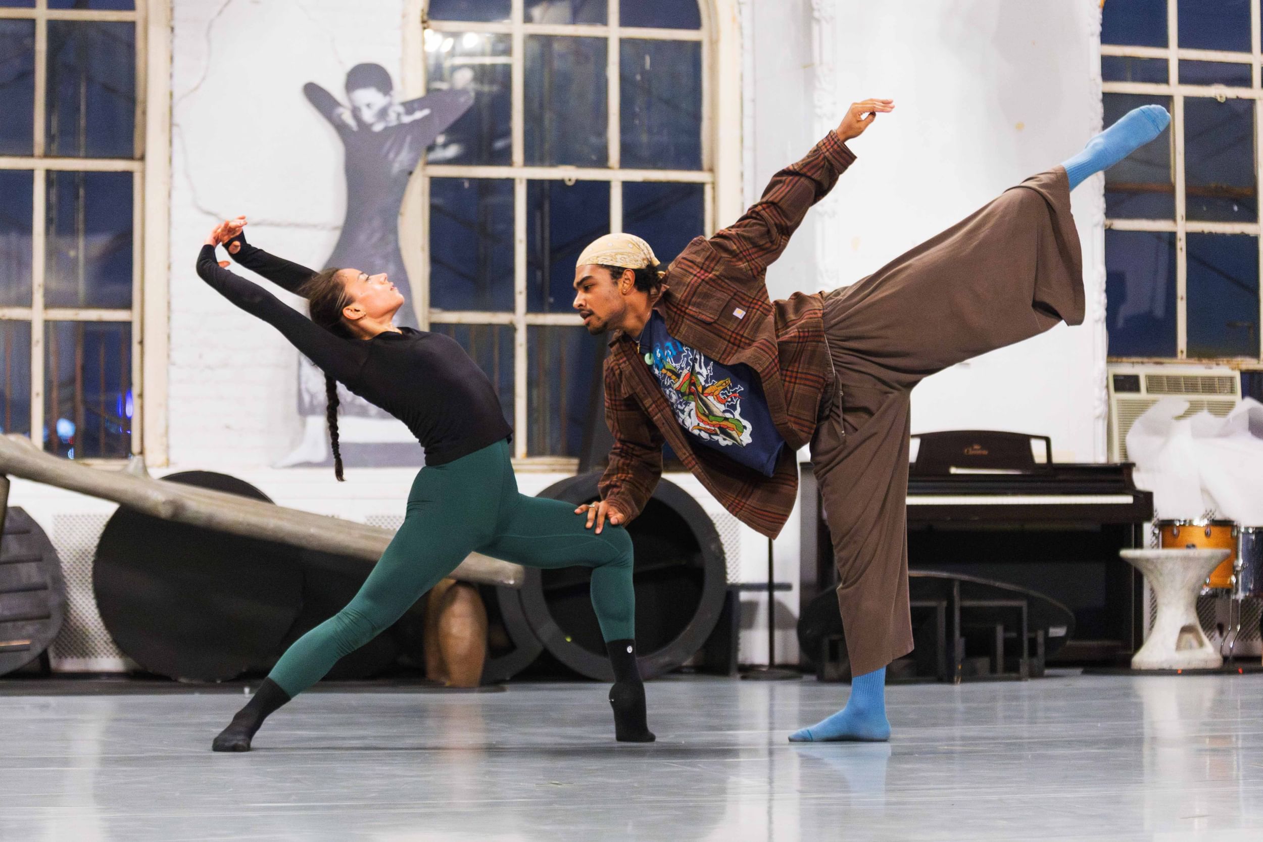 Two dancers in mid movement in an indoor rehearsal space