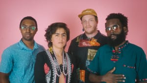 Four people pose for a photo wearing various colored clothing and accessories