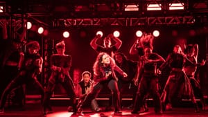 In a red-lit scene like a rock concert, McLeod, hand to her heart, dances passionately with 10 cast members.