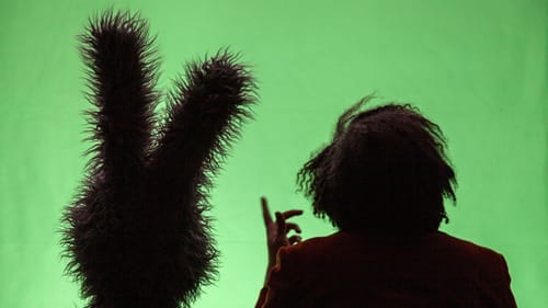 Ollie and Jay seen from behind, Mystery Science Theater style, silhouetted against a green screen.