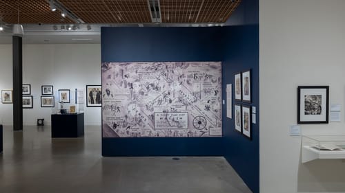 Gallery view featuring a huge reproduction of a 1932 map of Harlem on a dark blue wall, other artworks around it