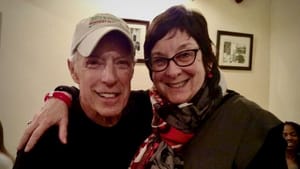 Photo of Blavat, in tan baseball hat, with Schaefer, in a red-patterned scarf. They’re smiling with an arm around each other