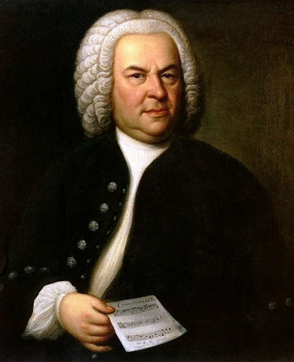 A portrait of Bach wearing a black robe over a white top, holding a sheet of music