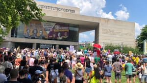 A crowd of about a thousand people attending a rally in front of the National Constitution Center on a hot summer day.