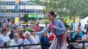 A dancer performs in front of a crowd outdoors during the day