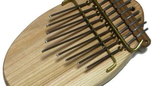 Close-up of a small kalimba on a white background. It's a wooden handheld instrument with metal tines played by your thumbs