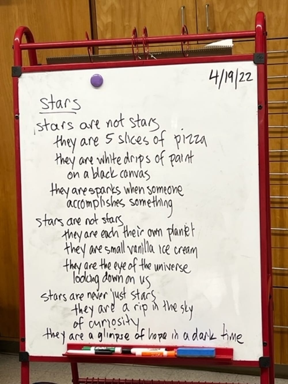 A fourth-grade classroom photo of a whiteboard with a collaboratively written poem about stars hand-written in black marker.