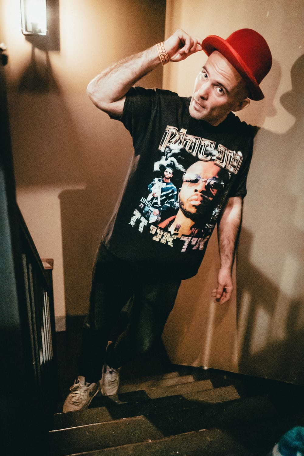 A portrait shot taken on indoor staircase, Kosha Dillz wearing a T-shirt with a performer’s face on it