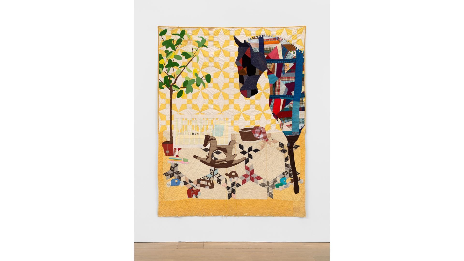 Quilt with a large patterned horse in profile at right, over a crib and small rocking horse and small green tree