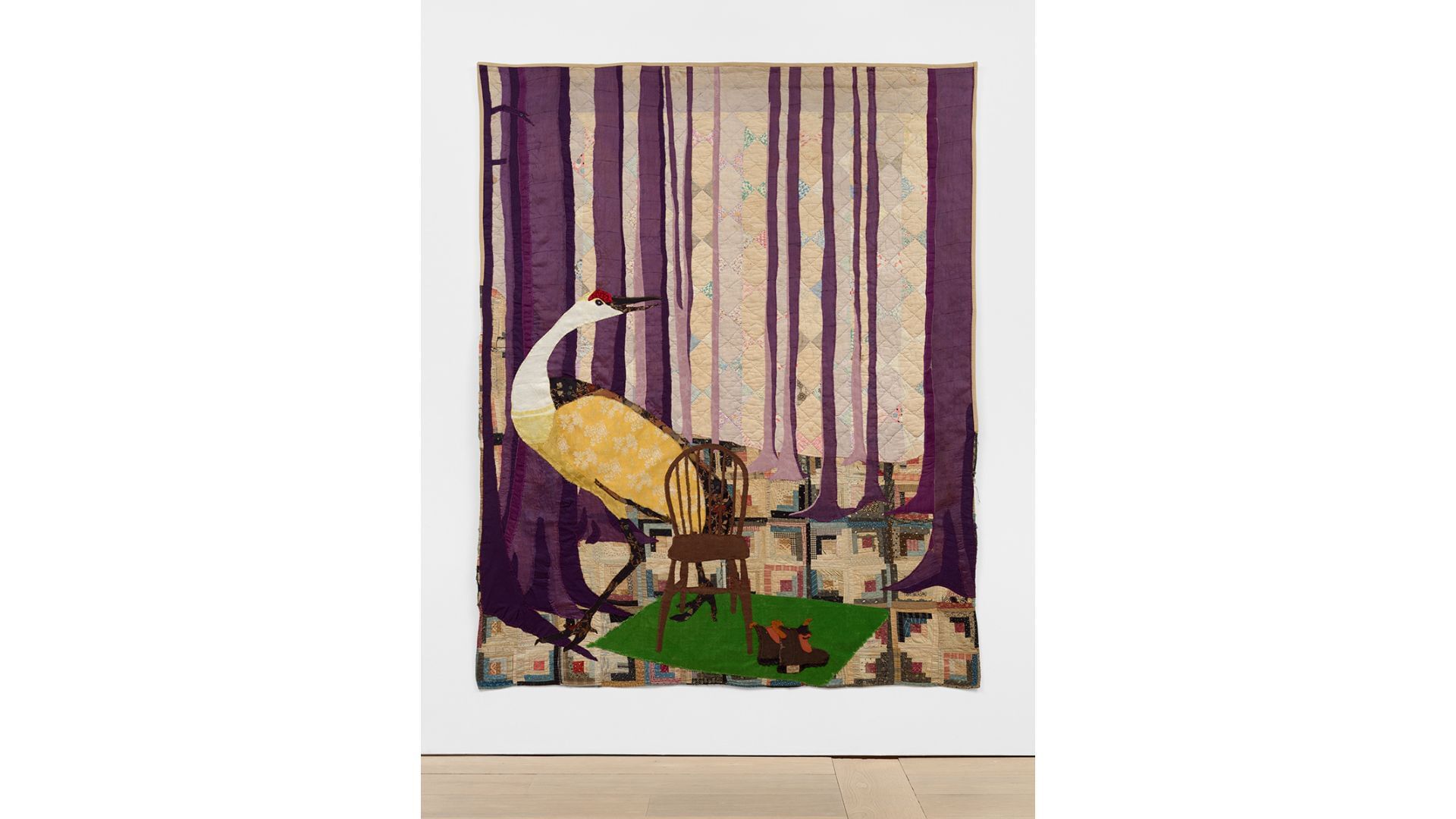 Quilt with long purple bars for tree trunks, a chair on a green blanket next to boots, and a large crane bird.