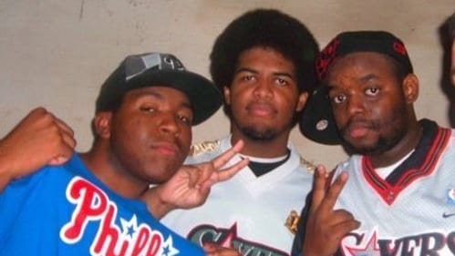 Three friends pose straight-faced, including Hiller, who’s wearing a Phillies shirt. The others are wearing Sixers jerseys.