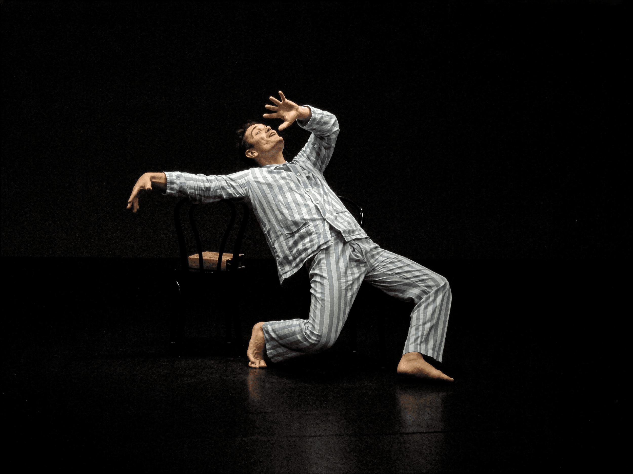 A man in striped pajamas strikes an elongated dramatic pose with all of his limbs at strange angles.