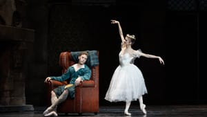 Thomas, in a green jacket and plaid kilt, naps in an armchair while Maslova, in full white tutu, poses with arms outstretched