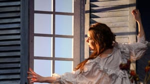 Ohse, a white woman with her back to the camera, in a voluminous nightdress, opens a window with large wooden shutters.