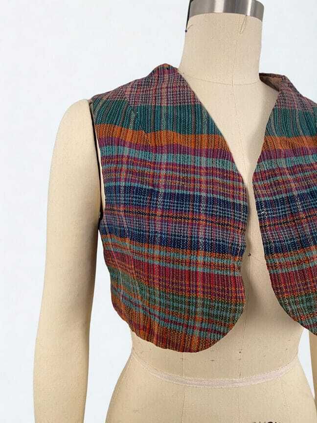 A cropped, gracefully shaped plaid vest in a surprising mix of green, orange, blue, and magenta shades.
