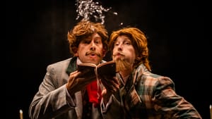 In tailored jackets and messy brown wigs, Sheppard and Yorke crowd behind an open book that Sheppard holds, and blow on it.
