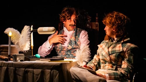 Closeup on Sheppard & Yorke talking earnestly at a cluttered table, wearing cheesy wigs and Victorian clothes.