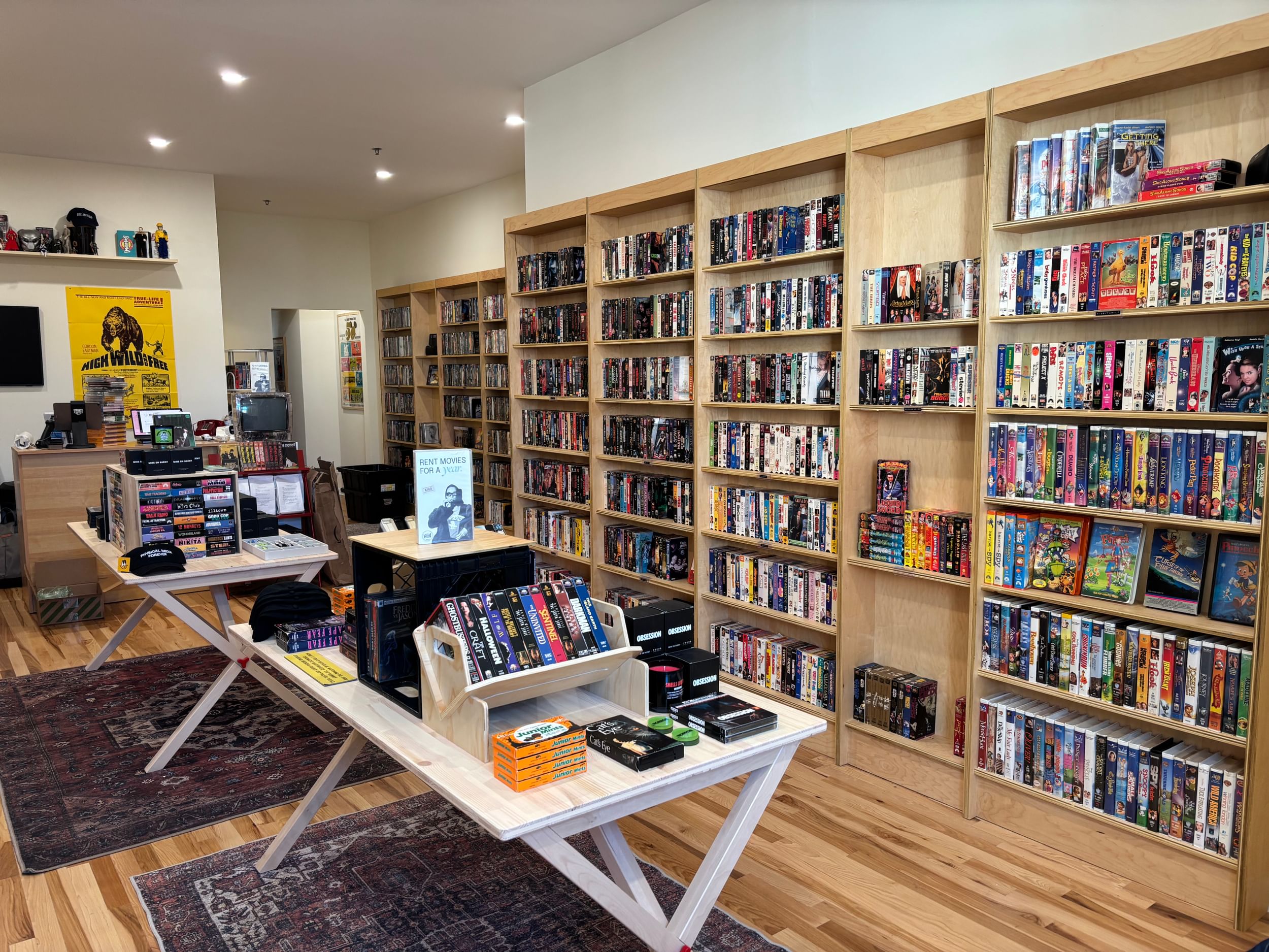 Light oak shelves and white tables are filled with DVDs, BluRays, and VHS tapes in the new small movie shop in South Philly.