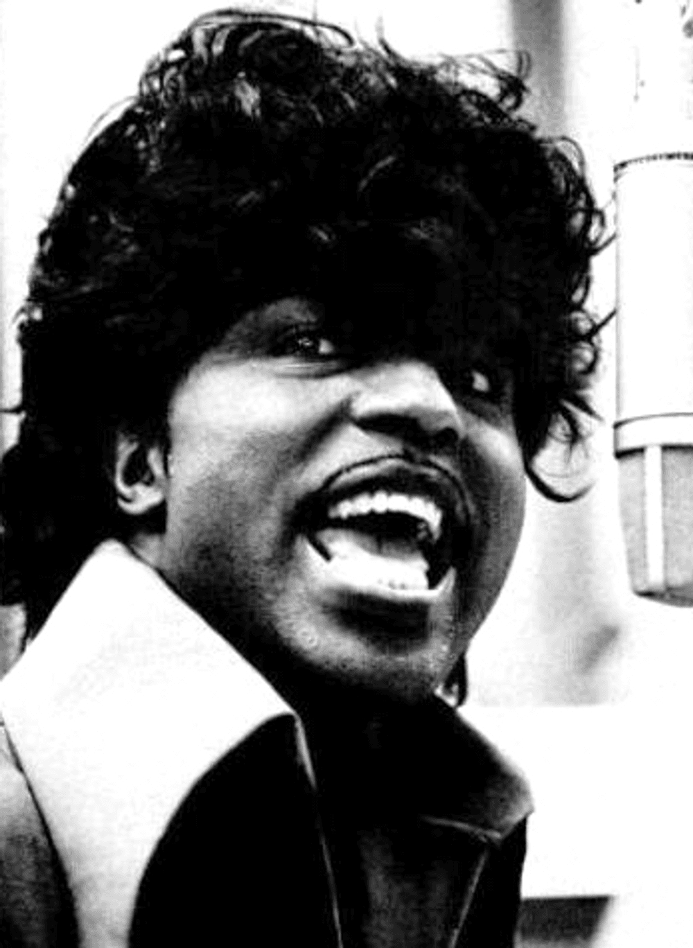 A black and white closeup snapshot of Little Richard, his mouth wide, expressive.