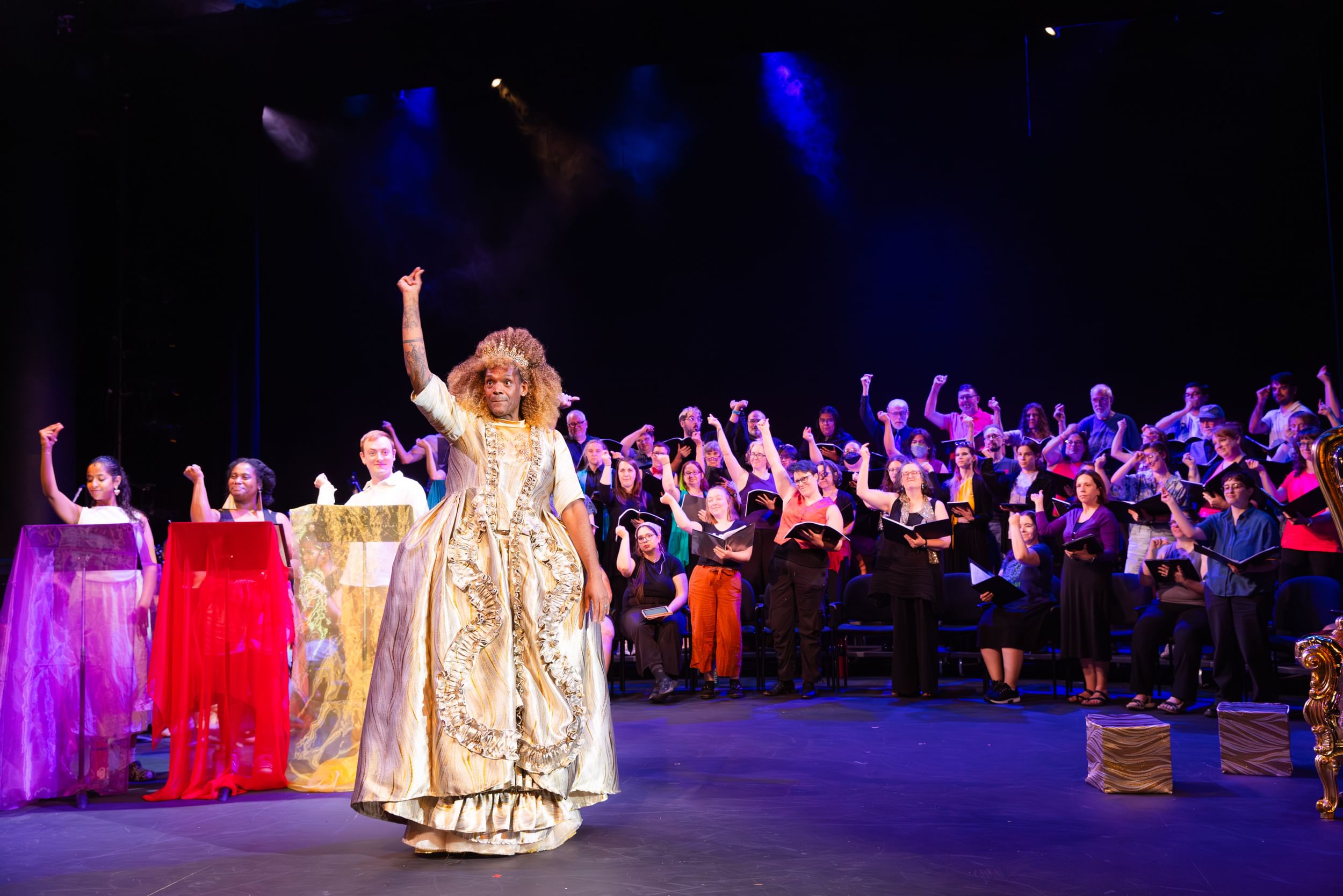 Diorio, a tall Black drag queen in a gold 18th-century gown, snaps flamboyantly in sync with dozens of singers around her.