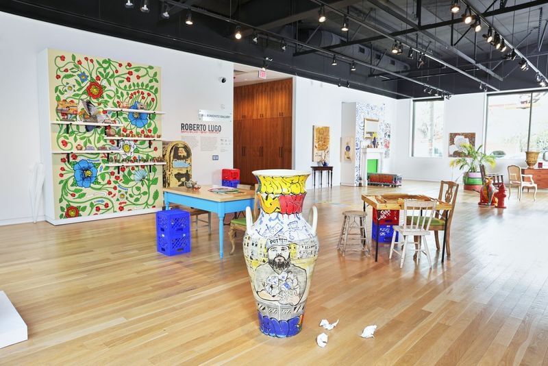 Eclectic furniture constellations on the gallery’s light wood floor, with a 5-foot urn painted in graffiti style at center