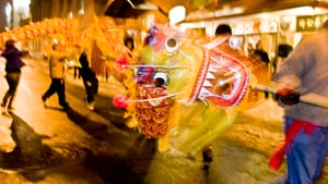 A Chinese dragon is carried outdoors at night in the street in Chinatown