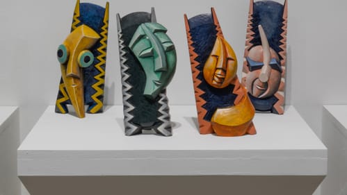Gallery view of Family Tree: four expressive, goofy, fantastical faces painted yellow, turquoise, orange & pink