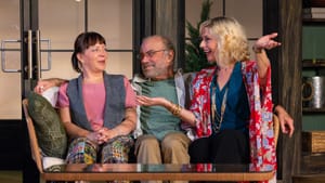 The three actors sit squished together on a small sofa, chatting happily.