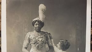 Vintage black & white photo of the very tall Williams in a lavish sequined dress, a white woman reaching up to her shoulder