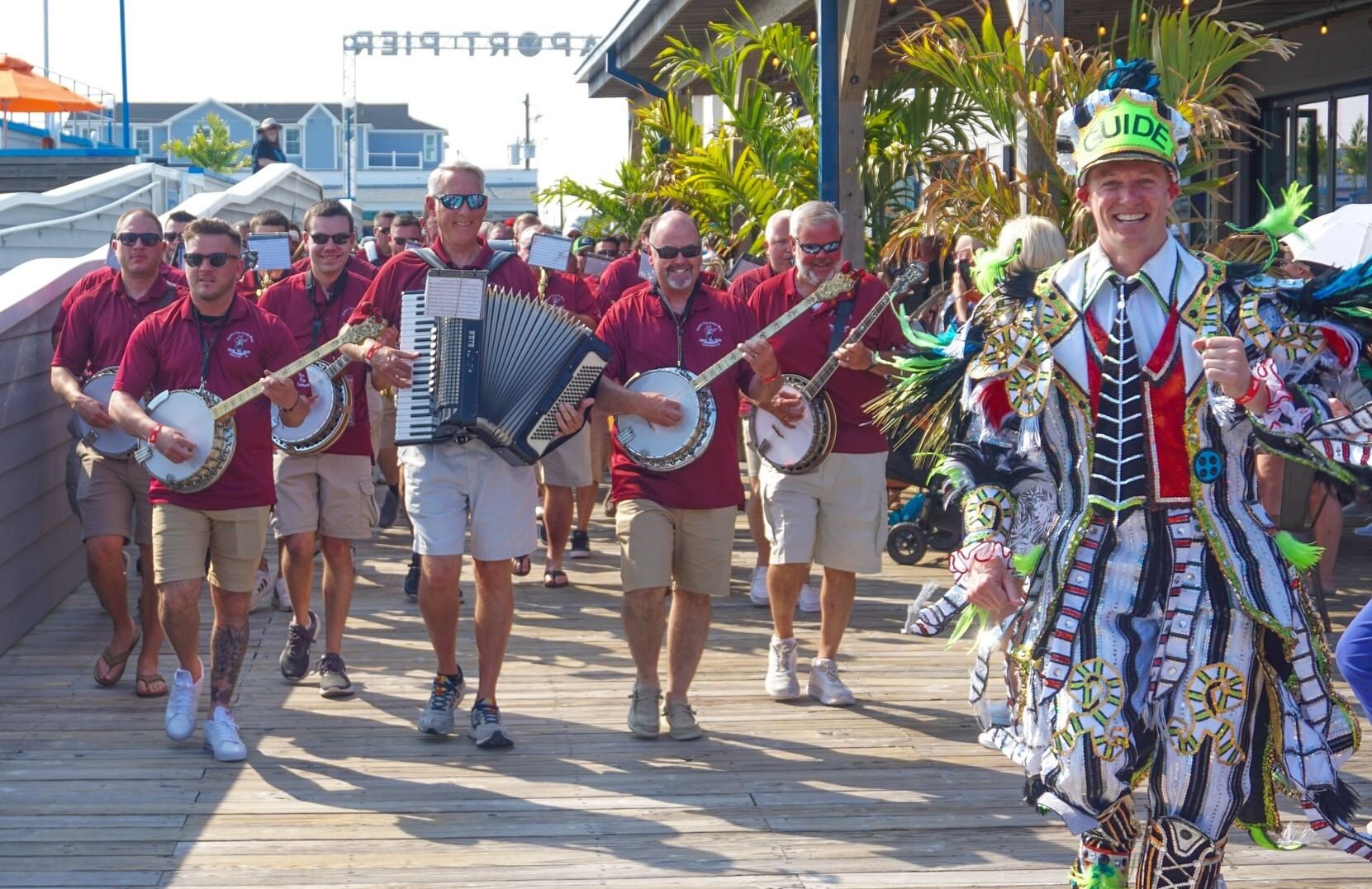 With one smiling man in a sequined, feathered costume at front, a few dozen walking men in maroon shirts play instruments.