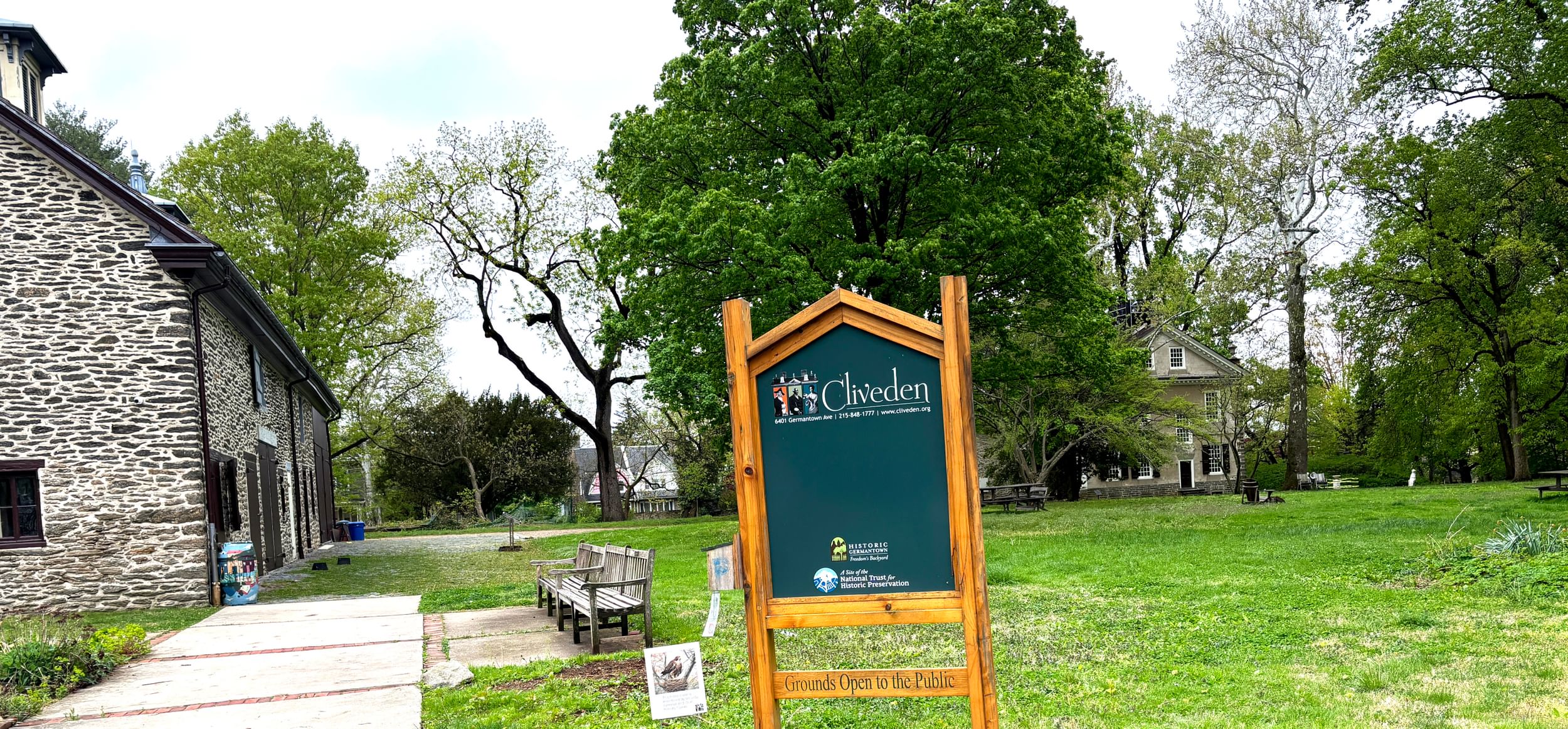 Outdoor view of a green park with historic 18th-century houses nestled among trees.