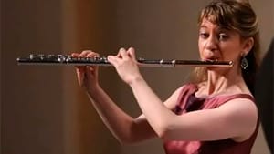 Stillman in formal dress plays the flute on stage.