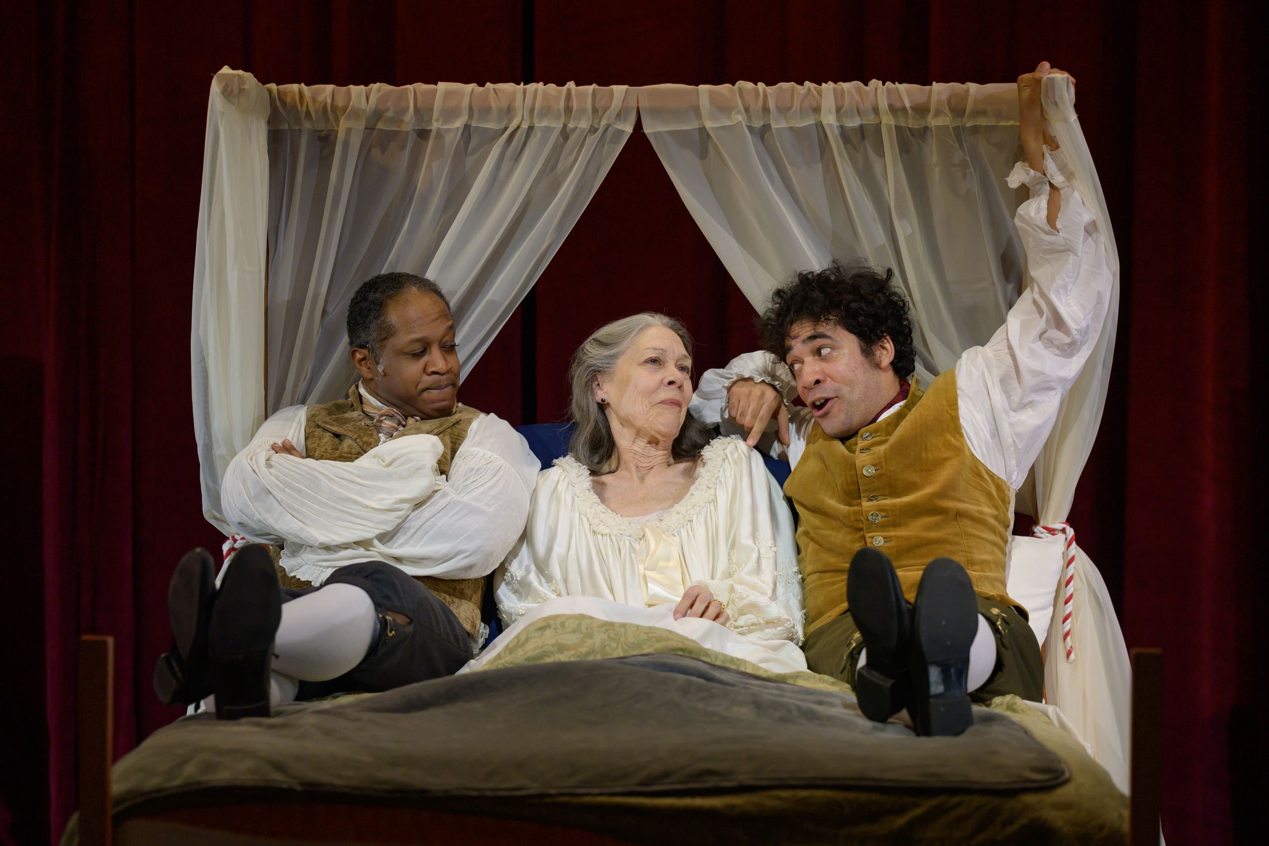 In 18th-century garb, the 2 actors lie side by side in a curtained bed, Boykin in a white nightdress. Briggs speaks to her